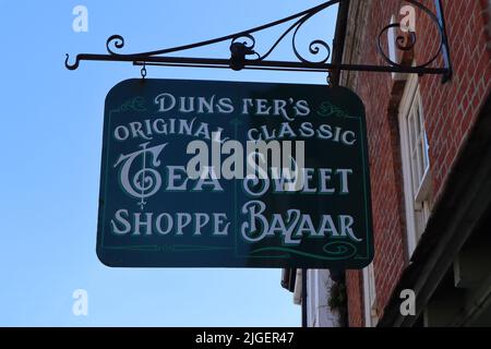 Das hängende Schild vor einem Teeladen und einem süßen Basar in der High Street von Dunster in Somerset, England Stockfoto