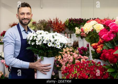 Ein Mitarbeiter der Großhandelsbasis für den Verkauf von Blumen hält eine riesige Vase mit Blumensträußen in den Händen Stockfoto