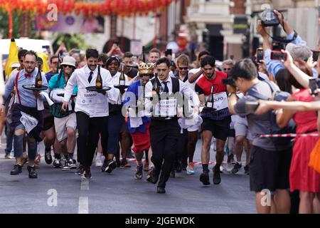 Die Menschen nehmen am Soho Waiter's Race im Soho Village Fete, Wardour Street, London, Teil. Eine Hundeschau, ein Spaghetti-Fressen-Wettbewerb und ein Kriegsschlepper der Polizei gegen die Feuerwehr sind alle Teil der Festivites auf dem Fete. Bilddatum: Sonntag, 10. Juli 2022. Stockfoto