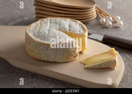 Weicher französischer Schafskäse und ein Stück auf einem Schneidebrett für einen Snack aus der Nähe Stockfoto