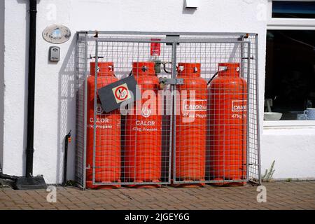 Vier große Propangasflaschen in einem Schutzkäfig zur Beheizung des Wohnsitzes. Stockfoto