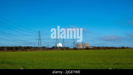 Sizewell Kernkraftwerke in weiter Ferne mit grünen Feldern im Vordergrund mit vielen Stromleitungen Stockfoto