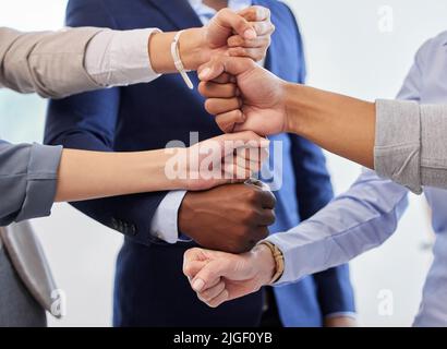 Wir können alles tun, was wir uns denken: Eine Gruppe von nicht erkennbaren Geschäftsleuten, die ihre Hände übereinander stapeln. Stockfoto