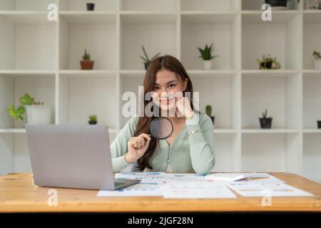 Business Analyst mit Lupe zur Überprüfung von Finanzdiagrammen und Diagrammen. Konzept der Analyse der Investitionsrendite und des Wachstums der Geschäftsanalyse. Stockfoto