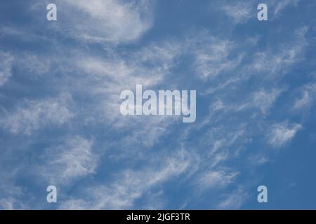 Ein strahlend blauer Himmel mit weißen, wispigen Wolken Stockfoto