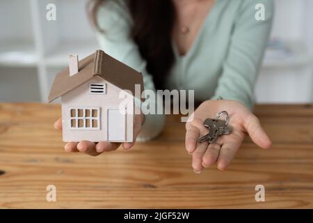 Close up Hand des Immobilienmaklers Übergabe der Schlüssel zu Hause Modell, Konzept für den Verkauf oder Umzug nach Hause Stockfoto