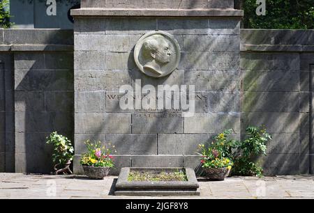 Stahnsdorf, Deutschland. 02.. Mai 2022. Blumen stehen am Grab von Werner von Siemens am Rande eines Pfades im Südwestkirchhof der Berliner Stadtsynode. Der Friedhof südwestlich von Berlin ist mit mehr als 200 Hektar der zweitgrößte in Deutschland. Aufgrund seines Waldcharakters und seiner vielen historischen Grabstätten ist der Südwestkirchhof ein beliebtes Touristenziel. Für die Erhaltung des kulturell und kunsthistorisch bedeutsamen Ortes wurde 2000 ein Förderverein gegründet. Quelle: Soeren Stache/dpa/Alamy Live News Stockfoto