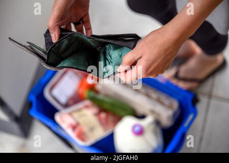 Eine Frau hatte nach einem einfachen Einkauf vor dem Zahltag eine leere Brieftasche. Sie überprüft ihre Geldbörse, hat aber kein Bargeld oder ein Kreditauto Stockfoto