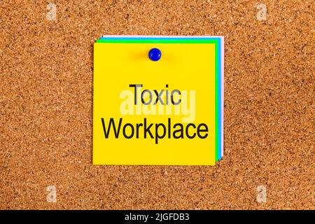 Gelbe Note mit den Worten giftig Arbeitsplatz auf einem Korkbrett Stockfoto