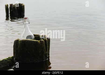 Glasflasche in einen alten Holzbalken gelegt. Symbol für Unentdeckt. Stockfoto