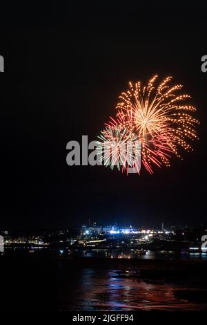 Feuerwerk von den britischen Feuerwerkmeisterschaften explodiert über der beleuchteten Stadt Plymouth, Cornwall. Stockfoto