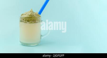 Dalgona Matcha Latte, blauer Hintergrund. Matcha grüner Tee. Trendiges Getränk. Superfoods. Milchgetränk. Koreanischer Drink Stockfoto