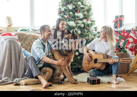 Weihnachts-Familienportrait zu Hause Urlaub Wohnzimmer, Kind und Hund spielen, Geschenk-Geschenkbox, Haus dekorieren von Xmas Tree Stockfoto