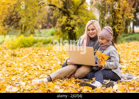 Online-Kommunikation. Familie mit Laptop und Videoanrufen, sitzt auf Picknickdecke im Garten. Stockfoto