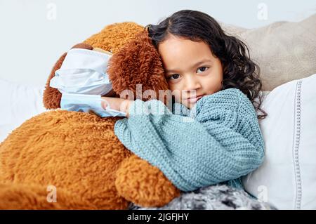 Kuscheln mit meinem Lieblings-Teddy. Ein kleines Mädchen kuschelt ihren Teddy zu Hause im Bett. Stockfoto