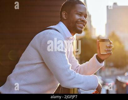 Seien Sie dankbar, optimistisch und positiv über das Leben. Ein junger Geschäftsmann, der Kaffee trinkt, während er auf dem Balkon eines Büros steht. Stockfoto