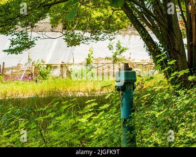 Nahaufnahme eines altmodischen Hydranten Ein alter Hydrant neben dem Bürgersteig eines Wohnkomplexes Stockfoto