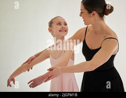 Entwickeln von Selbstvertrauen und Stolz auf sich selbst. ein junges Mädchen übt Ballett mit ihrer Lehrerin in einem Tanzstudio. Stockfoto