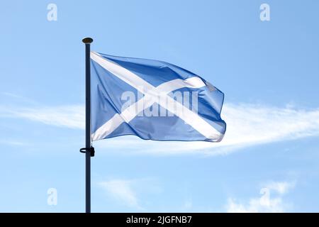 Schottische Saltyre-Flagge (St. Andreaskreuz) winkt über seinem Pol gegen einen blauen Himmel. Stockfoto