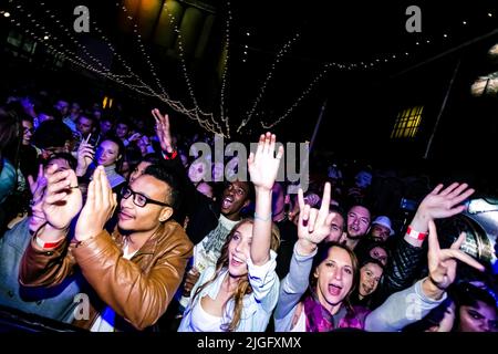 Eine Gruppe von trendigen jungen Leuten, die bei einem Musikkonzert dabei sind und Spaß haben Stockfoto