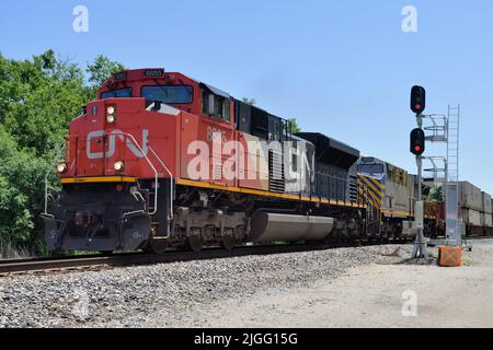 Dundee, Illinois, USA. Die Lokomotiven der Canadian National Railway führen einen intermodalen Güterzug durch einen vorbeifahrenden Abstellgleis. Stockfoto