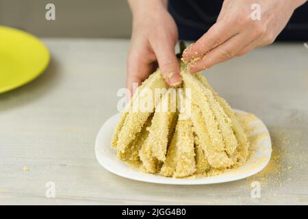 Beschichtung von geschnittener Aubergine mit Paniermehl. Frau kocht leckere Snacks zu Hause. Stockfoto