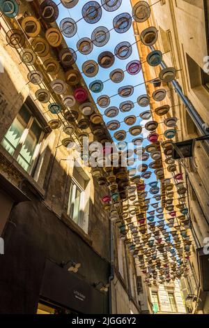 Die Einkaufsstraße Rue du Vieux Sextier in Avignon ist mit bunten Hüten bedeckt. Avignon, Frankreich Stockfoto