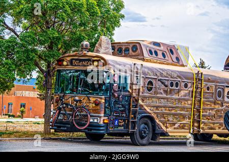 2021 05 21 Taos NM USA Steampunk umgebauter Kunstbus für Reise- und Selbstmordbewusstsein mit Unterschriften auf dem ganzen Bus und Fahrrad vorne befestigt Stockfoto