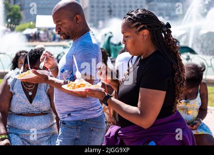 Chicago, USA. 9.. Juli 2022. Ein Paar genießt Trichterkuchen während des Probieren von Chicago im Grant Park in Chicago, USA, am 9. Juli 2022. Nach zwei Jahren kehrte Taste of Chicago 2022 mit mehr als 30 Lebensmittelhändlern, einer eigens dafür vorgesehenen Bierhalle, einem Weinzelt und einer Cocktailbar in den Grant Park zurück. Quelle: Joel Lerner/Xinhua/Alamy Live News Stockfoto