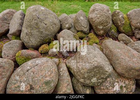 Nahaufnahme einer Steinmauer aus Felsbrocken und Felsen draußen. Hintergrund aus rustikalem, ländlichem Gebäude und Mauerwerk. Historisches Wohndesign oder Stockfoto