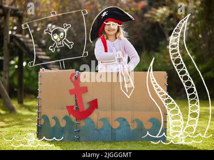 Spaß in der Sonne. Ein kleines Mädchen verkleidet wie ein Pirat draußen auf dem Hof. Stockfoto