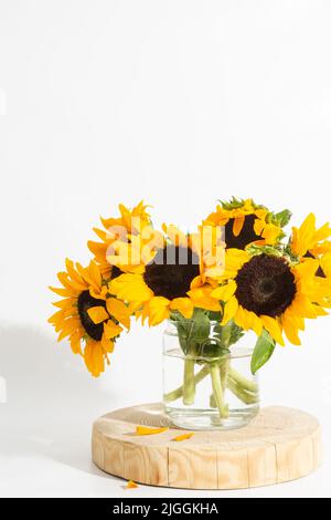 Helle Sonnenblumen in Glasvase auf weißem Hintergrund Stockfoto