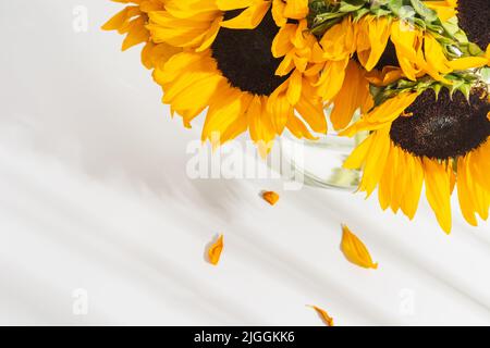 Draufsicht auf Sonnenblumenstrauß in Glasvase mit Schatten Stockfoto