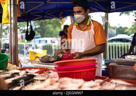 Kuala Lumpur, Malaysia - 21. Juni 2022: Fischverkäufer auf einem Frischmarkt in KL. Der Fischhändler verkauft seinen frischen Fang auf einem Nachtmarkt. Traditionelle Lebensmittelmarke Stockfoto