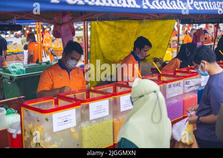 Kuala Lumpur, Malaysia - 21. Juni 2022: Zwei junge Männer bereiten Eisfruchtsaft für den Verkauf vor. Auf einem traditionellen Street-Food-Markt in der malaysischen Hauptstadt Stockfoto