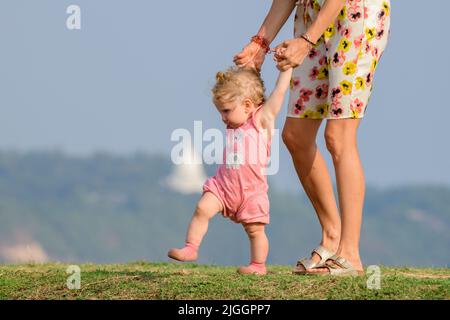 Galle, Sri Lanka - 02 15 2022: Bezauberndes kaukasisches Baby, das mit der Hilfe der Mutter spazieren lernt. Stockfoto