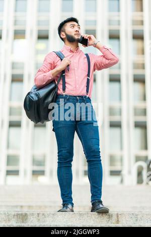 Asiatischer Mann mit lässiger Kleidung im Gespräch mit dem Handy Stockfoto