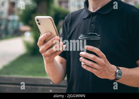 Nahaufnahme, Smartphone und ein Glas Kaffee in den Händen eines Mannes. Stockfoto