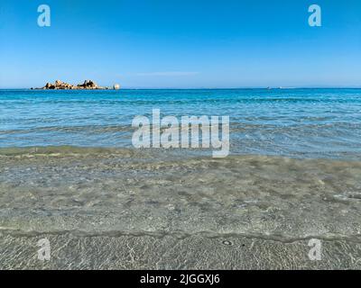Schöner Strand mit türkisfarbenem Wasser und einem Felsen im Hintergrund Stockfoto