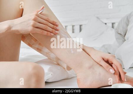 Nahaufnahme der Anwendung feuchtigkeitsspendende Lotion nach Enthaarung. Epilierkonzept Stockfoto