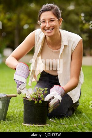 Ein Lächeln für die Nahrung. Porträt einer lächelnden Frau, die kniet, während sie im Garten arbeitet. Stockfoto