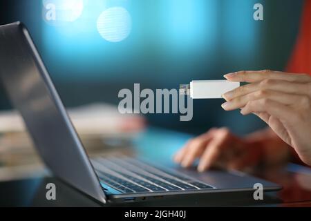 Nahaufnahme einer Frau, die nachts zu Hause einen Laptop mit der Hand und einem USB-Stick benutzt Stockfoto