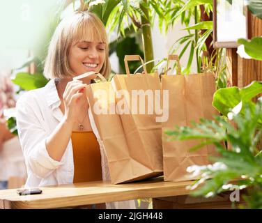 Ich habe alles zum Verkauf. Eine junge Frau, die in einem Café mit Einkaufstaschen sitzt. Stockfoto