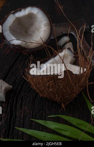 Gehackte Kokosnuss auf einem hölzernen Hintergrund, Draufsicht. Kokosmilch und Kokosflocken sind tropische Lebensmittel Stockfoto