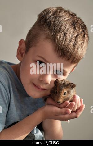 Nettes glücklich lächelndes weißes Kind, das mit seinem Haustier spielt. Stockfoto