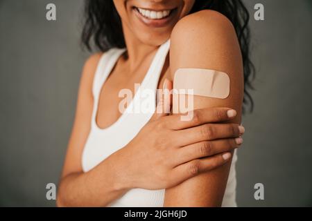 Nahaufnahme der Bandhilfe auf dem multiethnischen weiblichen Arm Stockfoto