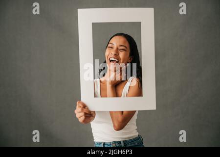 Lachend lächelnd Nahaufnahme einer multiethnischen Frau, die einen Rahmen hält Stockfoto