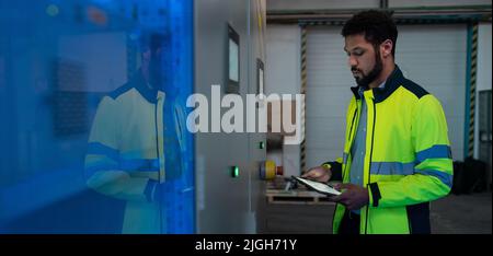 Junger Industriearbeiter, der CNC-Maschine bei der Metallbearbeitungsindustrie betreibt Stockfoto