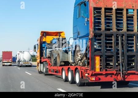 POV schweren Flurförderzeug Sattelauflieger Flachbett Plattform Transport zerstörte Bergungs LKW-Chassis und Kabine Maschine auf der gemeinsamen Autobahn Straße bei hell Stockfoto