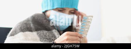 Frau hält Blister mit Tabletten in der Hand, fühlen sich unwohl, starke Kopfschmerzen Stockfoto